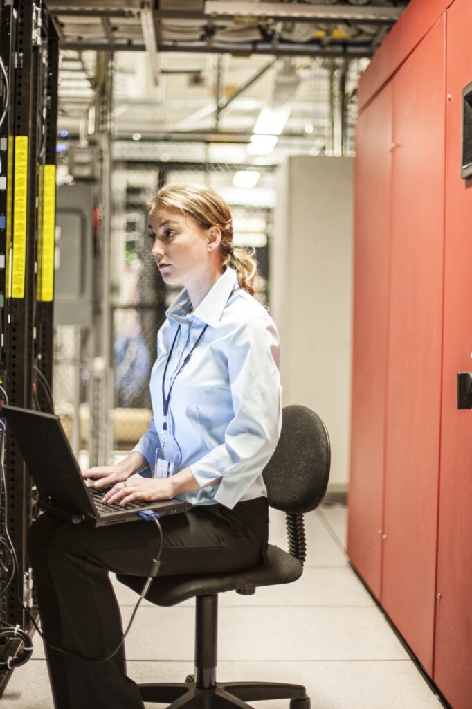 Caucasian woman technician working on computer servers in a server farm.